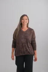 Sweter de punto color chocolate con cuello en V y diseño estampado con motivos botánicos en tonos más claros. Presenta mangas largas y un corte holgado con terminación acanalada en el ruedo.