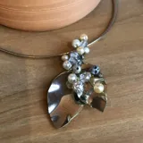 Gargantilla plateada con dije de dos hojas superpuestas y bordado de perlas y cristales.