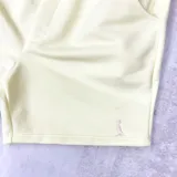 Short deportivo amarillo claro con cintura elástica ajustable con cordón y bolsillos laterales.