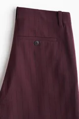 Pantalón de vestir de pierna ancha, color bordó oscuro, con finas rayas verticales en tono similar. Presenta cintura clásica con cierre de botón y bolsillos al bies.