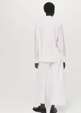 Camisa de lyocell color blanco, con cuello camisero, manga larga con puños abotonados, diseño recto y cierre frontal con botones ocultos.