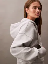 Buzo gris con capucha, cierre frontal con cremallera, logo de Calvin Klein bordado en el pecho y corte cropped.