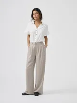 Pantalón sastrero de tiro alto color gris, con pinzas frontales y bolsillos laterales, de corte recto y holgado.