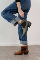 Botín negro de cuero con elásticos laterales, taco bajo y tirador trasero.