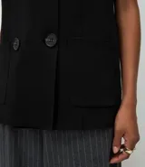 Chaleco alargado de Marfinno, confeccionado en tejido de punto con estructura encorpada. Presenta un diseño recto con cierre delantero cruzado de cuatro botones, dos bolsillos aplicados en el frente y sisa amplia.