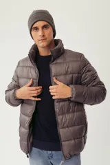 Campera puffer color gris con cuello elevado, cierre frontal completo y bolsillos laterales con cierre. Presenta logo en relieve en el pecho y diseño acolchado.