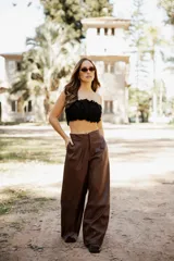 Pantalón de tiro alto confeccionado en cuero sintético color marrón chocolate, con corte amplio y diseño de pierna ancha.