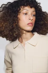 Jersey de punto con cuello tipo polo, manga larga con puños y cierre frontal con botones. Presenta un bolsillo de plastrón en el pecho y diseño de corte holgado.