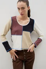 Remera de manga larga con diseño de bloques de color en tonos neutros, confeccionada con costuras externas visibles en color azul contrastante.