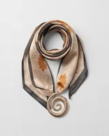 Pañuelo de seda con estampado de hojas y flores en tonos naranjas y grises sobre fondo beige, con bordes oscuros e incluye un dije dorado en forma de espiral.