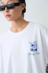 Remera de algodón gris melange con corte oversize, manga corta y estampa localizada en el frente con motivos deportivos en tonos verde y rosado.
