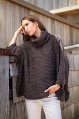 Sweater tipo poncho tejido en lana color marrón oscuro, con cuello alto y mangas 3/4. Diseño holgado y textura rústica.