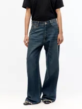 Jean de corte wide leg, confeccionado en denim 100% algodón, con diseño de cinco bolsillos y lavado oscuro con acabado desgastado.