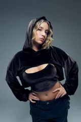 Canguro corto negro de terciopelo con capucha, mangas largas abullonadas con puños elastizados y abertura en el pecho.