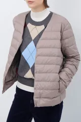 Campera acolchada tipo puffer en color beige, con diseño sin cuello y cierre frontal con botones a presión.