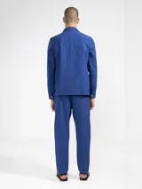 Pantalón de vestir color crema, confeccionado en tejido ligero de algodón con textura seersucker. Tiene corte recto, bolsillos laterales y traseros, cierre con botón y cremallera, y parche con logo de la marca.