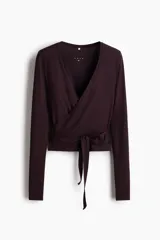 Top deportivo de manga larga confeccionado en modal suave de color bordó, con diseño cruzado, escote en V pronunciado, tiras para anudar en la cintura y corte ajustado.