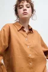 Camisa oversize de lino, color tostado, con cuello clásico, cierre frontal de botones y bolsillo en el pecho.