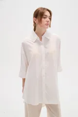 Camisa de lino blanca de corte holgado, con cuello camisero y mangas tres cuartos, diseñada con estilo casual.