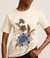 Blusa slim de mangas cortas, confeccionada en algodón, con cuello redondo y estampa floral con lettering caligráfico.