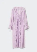 Vestido largo de tejido fluido y semitransparente color lila, con cuello en pico, mangas largas con volantes y cierre frontal con lazo. Presenta volantes decorativos a lo largo de la abertura frontal y fruncido elástico en la cintura.