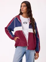 Campera rompevientos Rusty con diseño color block en tonos bordó, azul y blanco. Cuenta con cierre frontal, capucha con cordones ajustables, puños elásticos y logo bordado en el pecho.