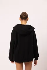 Campera reversible con capucha y cierre metálico frontal. Un lado está confeccionado en eco cuero negro con acabado brillante y el otro en corderito sintético negro. Cuenta con bolsillos laterales decorados con tachas piramidales plateadas, además de puños y cintura de rib elástico.