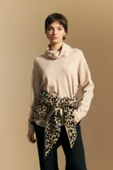 Polera de tejido de punto color beige con cuello alto de caída relajada, mangas largas con hombros caídos y diseño de líneas sutiles en la trama.