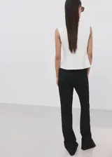 Camiseta sin mangas de color blanco, de diseño recto, con cuello redondo y hombreras, con corte peplum en la parte inferior.