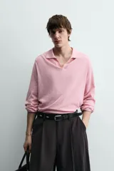 Polo de punto ligero color rosado, con cuello solapa, abertura frontal en V y manga larga.