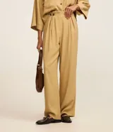 Pantalón recto de tiro alto color beige, confeccionado en viscosa, de diseño clásico y fluido con cierre frontal y bolsillos.