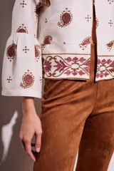 Blusa blanca con bordado de cachemir en negro, corte oversize y mangas acampanadas.