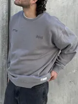 Buzo gris de corte oversize con cuello redondo y puños ajustados. Estampado en la espalda con la palabra "UNEXPECTED" y la frase "JOIN THE ROAD - POWER CONNECTION".