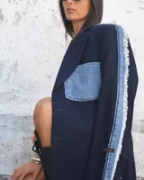 Blazer oversize de diseño, confeccionado en tela azul marino con detalles de denim deshilachado en las mangas y un bolsillo de parche de denim con logo bordado en el pecho.