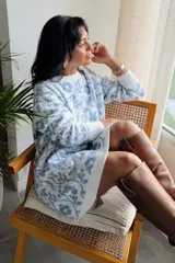 Suéter largo de punto con diseño floral en tonos blanco y azul, de corte holgado, cuello redondo y mangas largas con puños acanalados. Puede utilizarse como vestido tejido.
