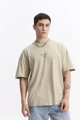 Remera de manga corta color beige, con escote redondo y estampado frontal con la palabra "Surreal" en tipografía cursiva.