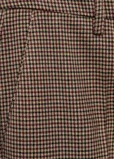 Pantalón de tiro medio con diseño crop, corte skinny y estampado a cuadros tipo tartán en tonos marrones y negros. Cuenta con trabillas en la cintura, bolsillos laterales y cierre oculto con botón, gancho y cremallera.