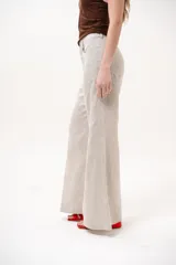 Pantalón color beige de corte wide leg, con bolsillos delanteros y cierre frontal de botón y cremallera.
