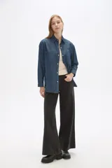 Sobrecamisa de jean en tono celeste claro, con cuello clásico, cierre frontal con botones metálicos y bolsillos frontales tipo parche.