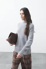 Polera de tejido de punto en color marrón oscuro, con cuello alto y diseño de silueta relajada.