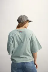 Remera color crema de corte holgado, con mangas cortas y costuras a la vista en color ocre.