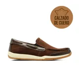 Mocasín estilo náutico de cuero marrón con detalles en cuero más oscuro, cordones laterales decorativos, costuras visibles y suela de goma blanca con base marrón.