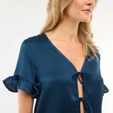 Conjunto de pijama compuesto por una blusa de manga corta con volados y cierre frontal mediante lazos, y un pantalón de corte recto con cintura elástica, confeccionado en tela con textura tipo crepé.