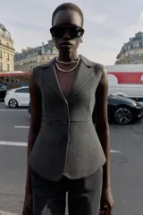 Chaleco entallado de punto color gris oscuro, con cuello solapa, manga sisa y cierre frontal de tres botones.