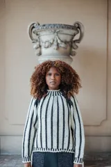 Sweater de punto en lana merino con diseño de rayas verticales en contraste blanco y negro, cuello alto y corte recto.