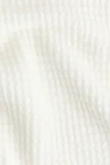 Top blanco de tejido de punto con textura waffle, escote bote y mangas cortas de diseño murciélago.