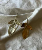 Par de aros colgantes hechos a mano en bronce, con forma de hojas texturizadas. Cierre con gancho.