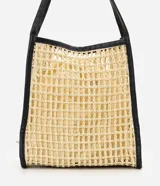 Cartera tipo shopper confeccionada en paja trenzada de color beige con detalles en negro, asas de hombro de poliuretano y compartimento interior con cierre de cordón ajustable.