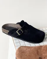 Zueco de cuero vacuno color negro, con diseño de punta cuadrada, hebilla metálica ajustable en el empeine y plantilla anatómica con base de corcho.