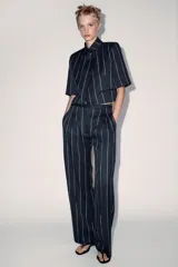 Pantalón de tiro medio de ZARA Woman Collection, confeccionado con mezcla de lino. Presenta diseño de rayas diplomáticas, bolsillos laterales, pinzas en el delantero y cierre frontal con cremallera, botón y ganchos metálicos.